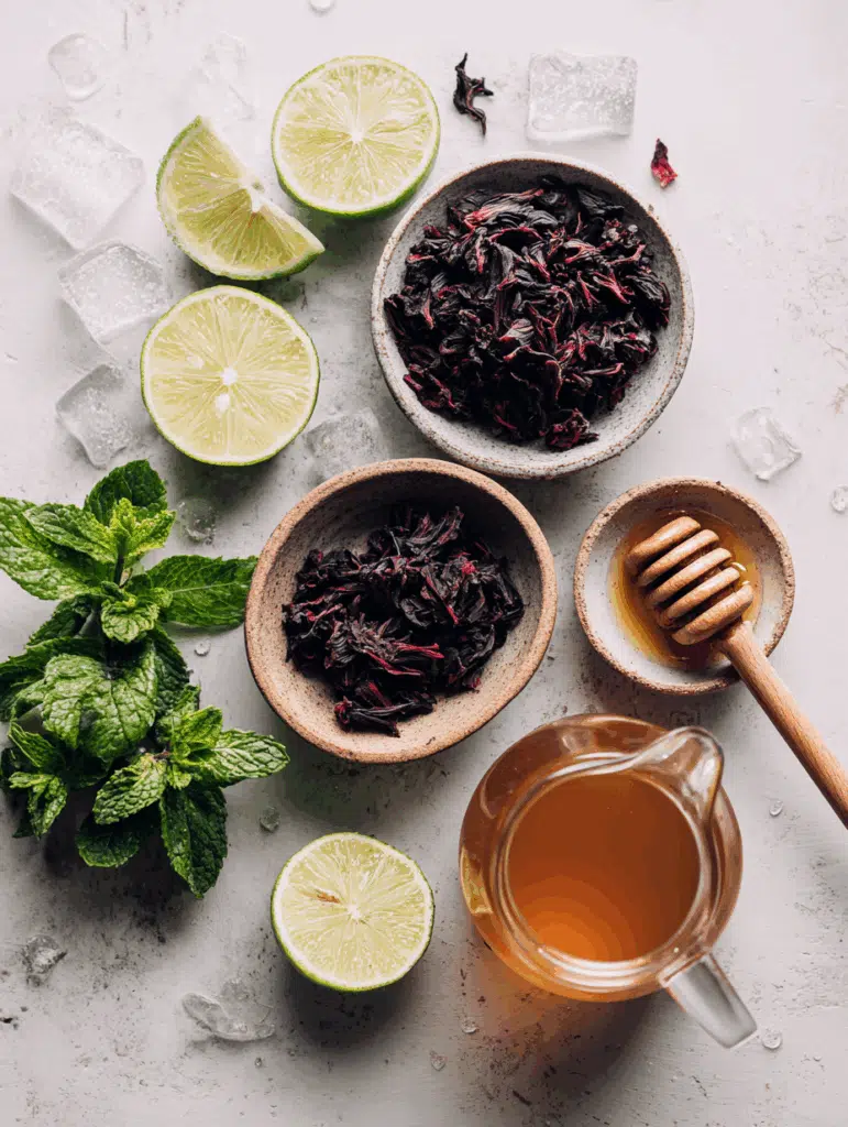 Ingredients for hibiscus cold brew tea including dried flowers, honey, and lime